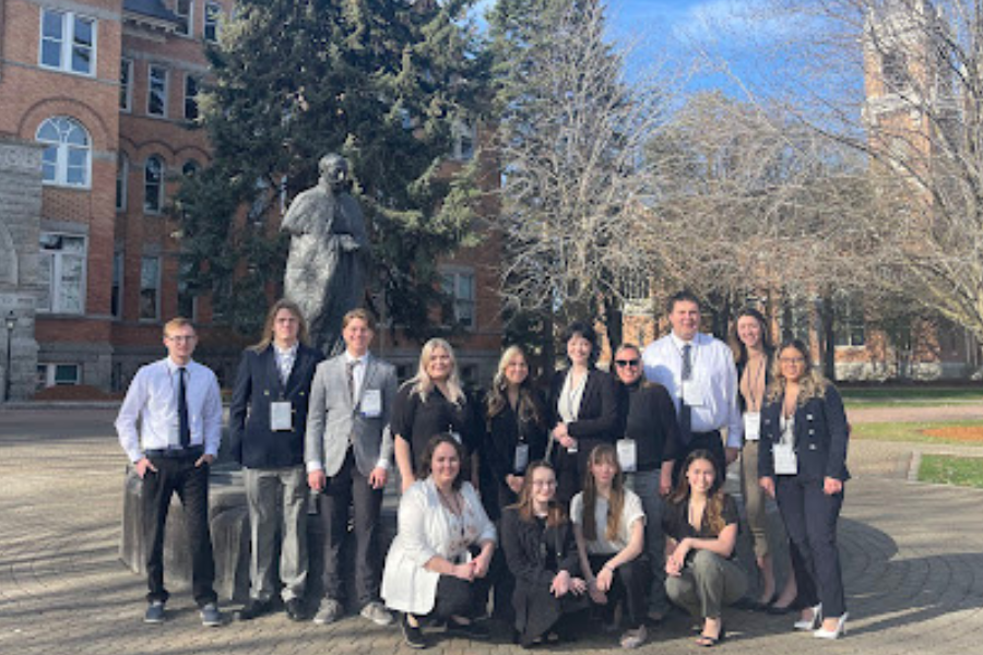 The NSAC team poses for a photo outside, in front of campus buildings and a statue in Spokane. WA